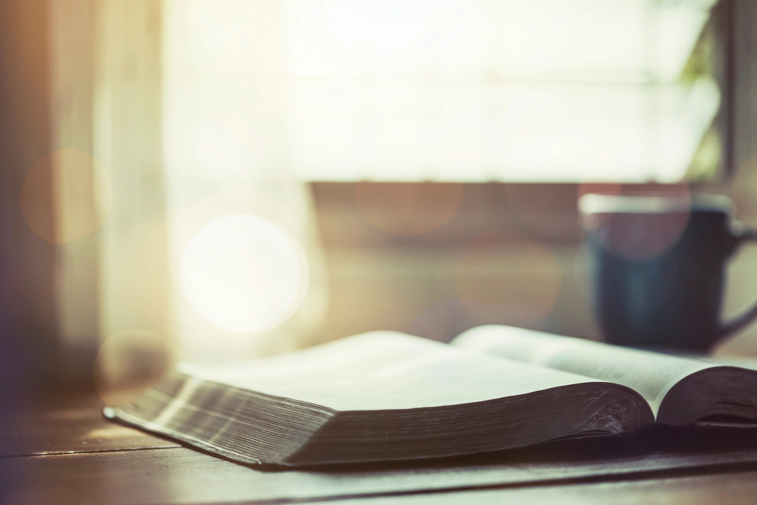 Open Bible with coffee on a wooden table for morning devotion